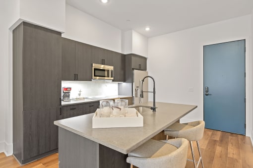 Kitchen with gray cabinets and a large island with a sink and two stools at Four23/Hoge, Ohio, 45226