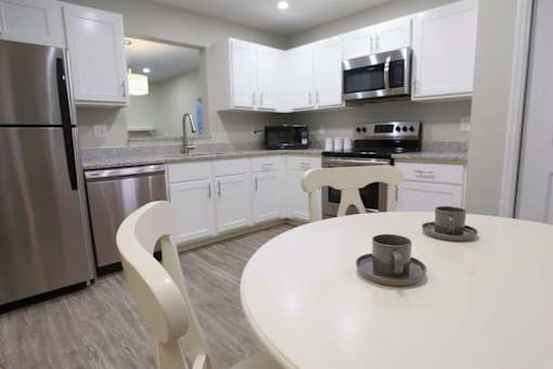 A white kitchen with a table and chairs.