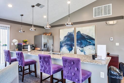 A kitchen with purple chairs and a painting of a mountain on the wall.