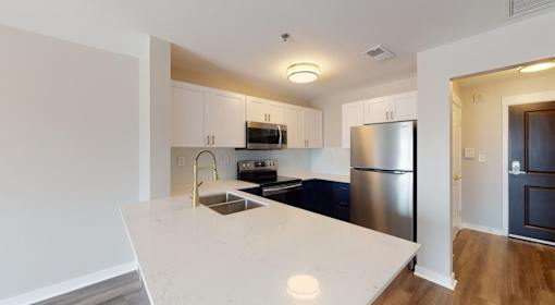 A kitchen with a white countertop and stainless steel appliances.