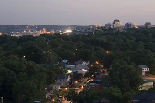 A cityscape at dusk with buildings and trees in the foreground.