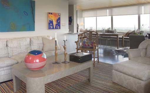 A living room with a couch, a table, and a painting on the wall.