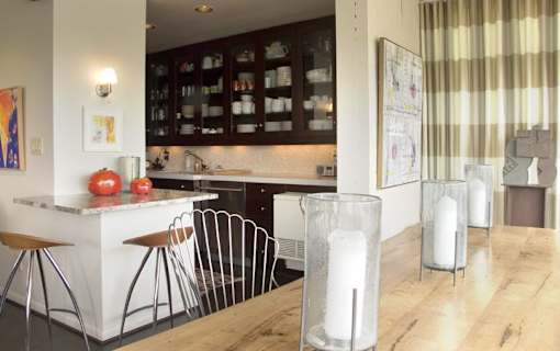 A kitchen with a white counter and brown chairs.