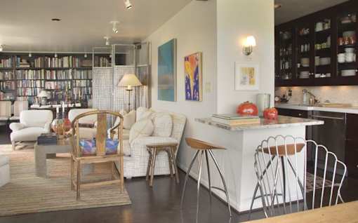 A modern living room with a kitchen area in the background.