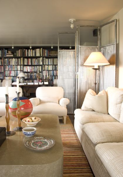 A living room with a white couch, a coffee table, and a bookshelf filled with books.