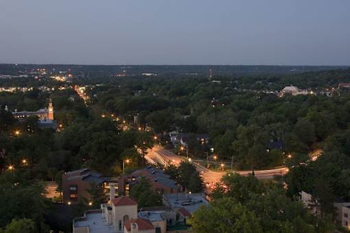 A cityscape at dusk with buildings and streets illuminated by lights.