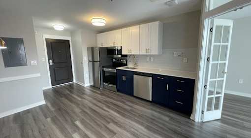A kitchen with dark wood floors and white walls.