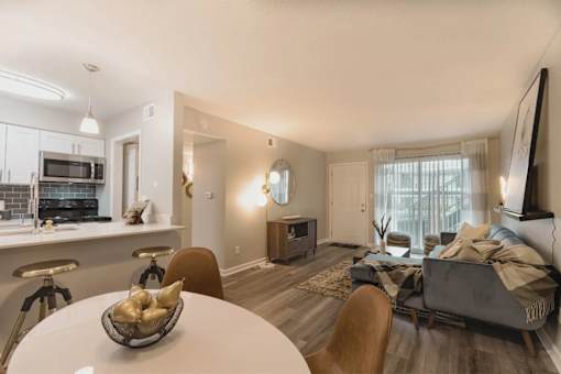 A modern living room with a grey couch and a white dining table at A62 Apartments, Indianapolis, Indiana