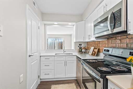 A kitchen with white cabinets and a brick backsplash.