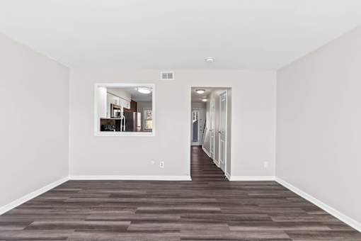 A long, empty hallway with a kitchen visible through the doorway.