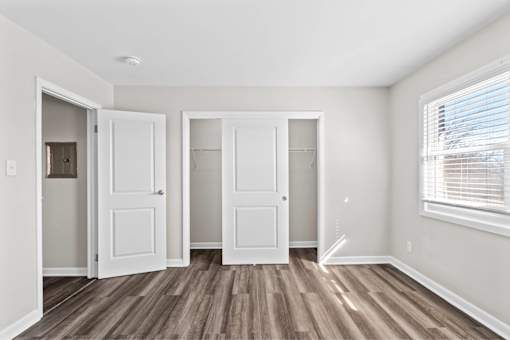 Three white doors are in a room with wood floors.