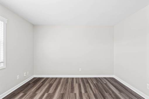 A room with wooden flooring and white walls.