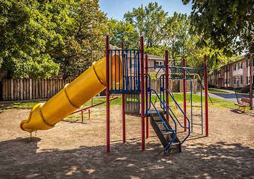 A playground with a yellow slide and a blue and red swing set.