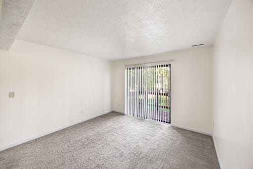 A room with white walls and a carpeted floor with a sliding glass door.