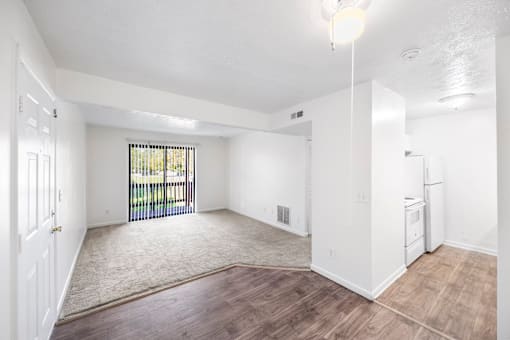 A spacious room with a window and sliding glass door.