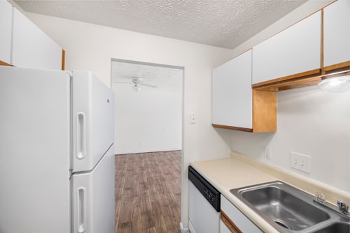 A kitchen with a white refrigerator and a sink.