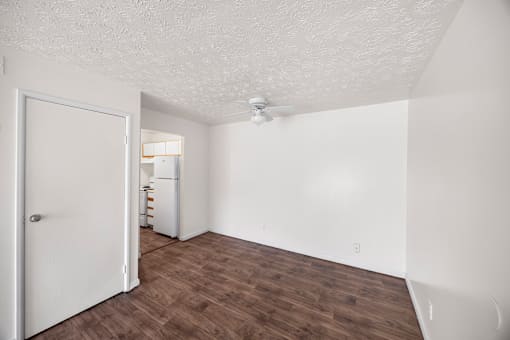 A room with a white door and wooden flooring.