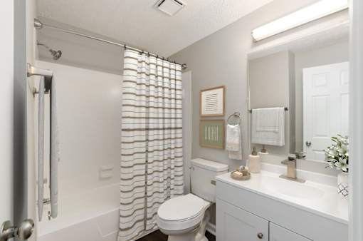 A white bathroom with a toilet, sink, and shower.