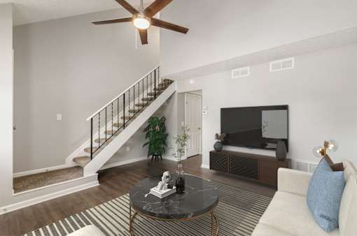 A living room with a staircase and a television.