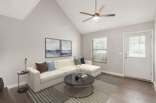 A living room with a white couch, a coffee table, and a ceiling fan.