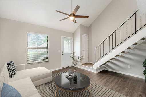 A living room with a couch, a table, and a ceiling fan.