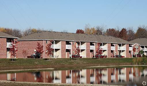 A building with a red brick exterior is reflected in the water in front of it.