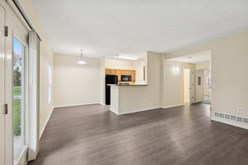 A spacious living room with a kitchenette in the background.