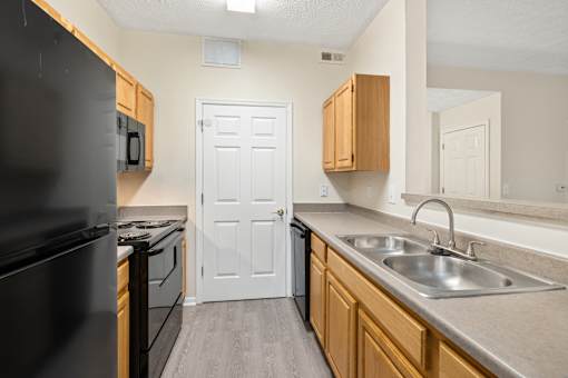 A kitchen with a black refrigerator and wooden cabinets.