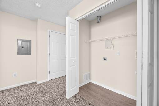 A room with a white door and a white wall with a light switch.
