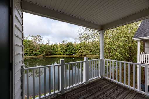 A porch with a view of a lake and trees.