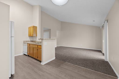 A kitchen area with a refrigerator, sink, and cabinets.