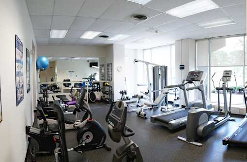 A gym with a variety of exercise equipment including treadmills, stationary bikes, and weight machines.
