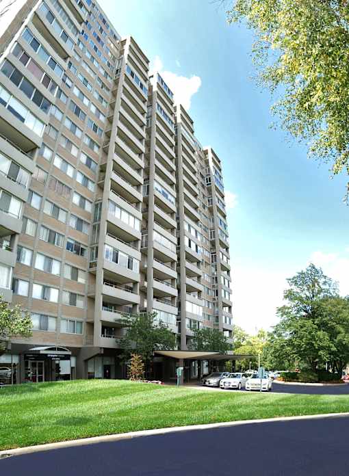 A tall residential building with a parking lot in front.