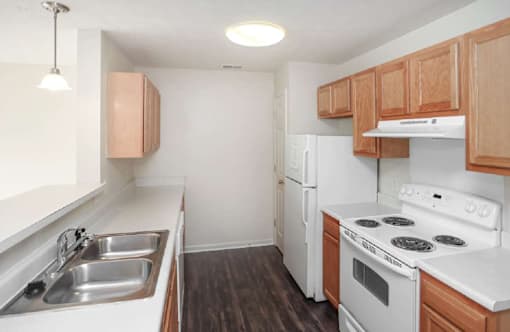 A kitchen with white appliances and wooden cabinets.