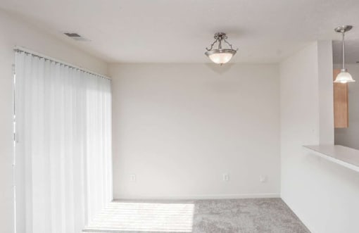 A room with a window covered by white curtains and a chandelier hanging from the ceiling.