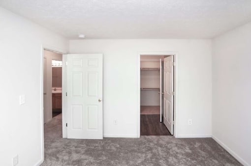 A room with a white door and a carpeted floor.