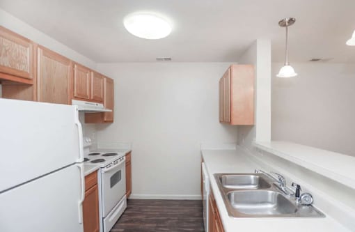 A kitchen with white appliances and wooden cabinets.