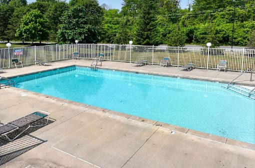 A large outdoor swimming pool surrounded by a metal fence.