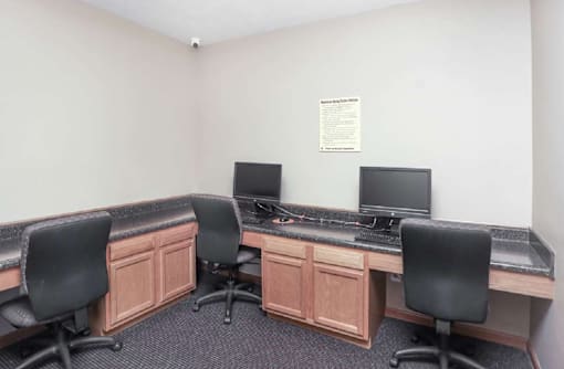 A small office with two computers and two chairs.
