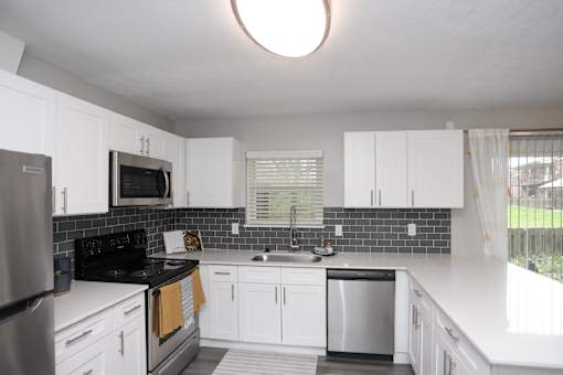 A kitchen with white cabinets and a black stove top oven.at Spinnaker Court, Indianapolis Indiana