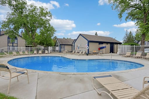 A small pool with a deck and a house in the background.