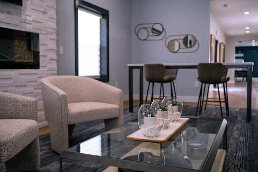 a living room with a glass coffee table and chairs and a kitchen with a bar at Ten31, Dayton, OH