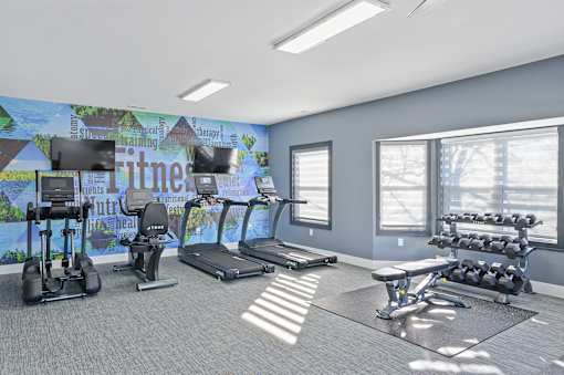 a gym with cardio machines and weights and a wall mural of gym equipment at Ten31, Dayton, OH, 45458
