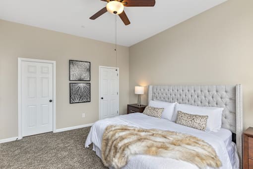 A bedroom with a large bed and a ceiling fan.