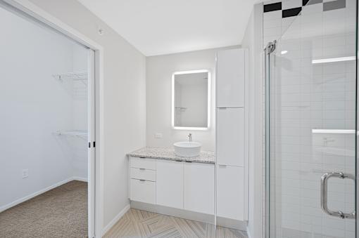 A bathroom with a sink, mirror, and cabinets at Sky Central Apartments, Cincinnati, OH, 45202