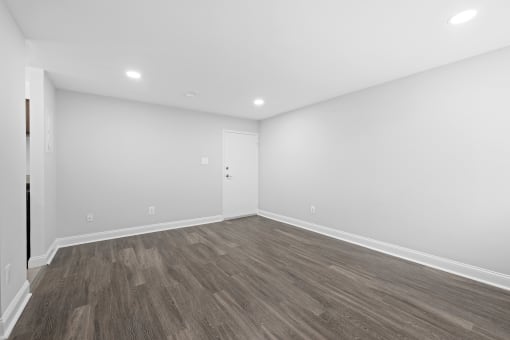 an empty living room with white walls and wood flooring