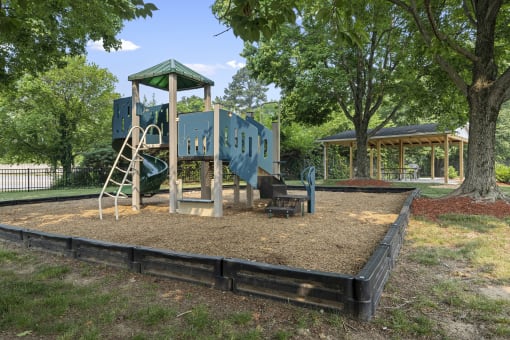 a playground with a blue playset and a swing set