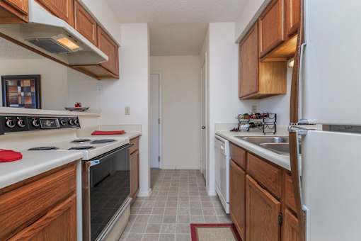 A kitchen with white appliances and wooden cabinets.
