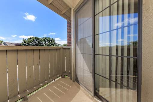 A balcony with a glass door and a wooden fence.