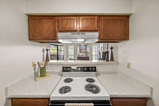 A kitchen with a stove top oven and wooden cabinets.
